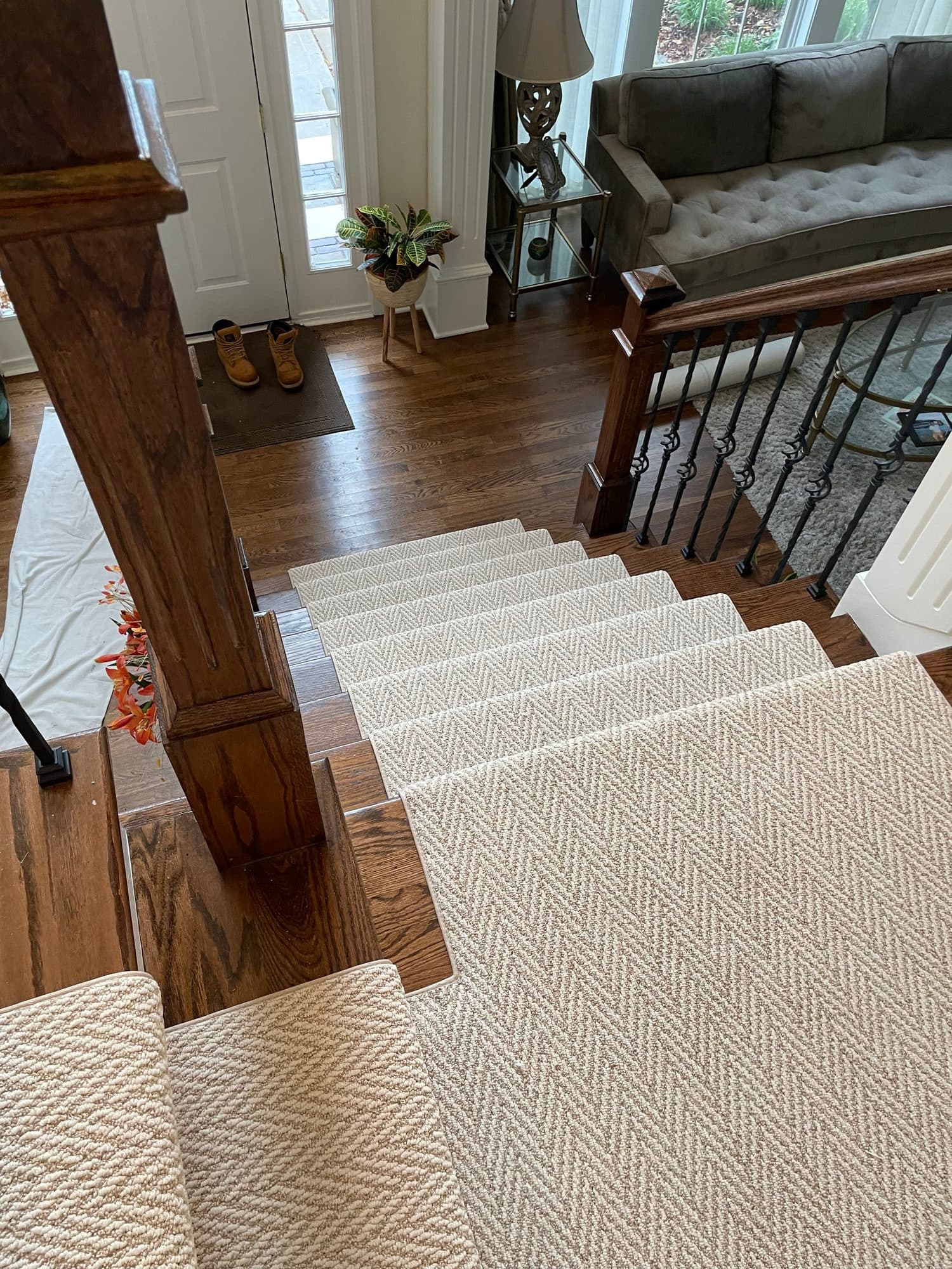 Herringbone carpet runner crossing the upstairs landing and continuing down the stairs toward the foyer and front door