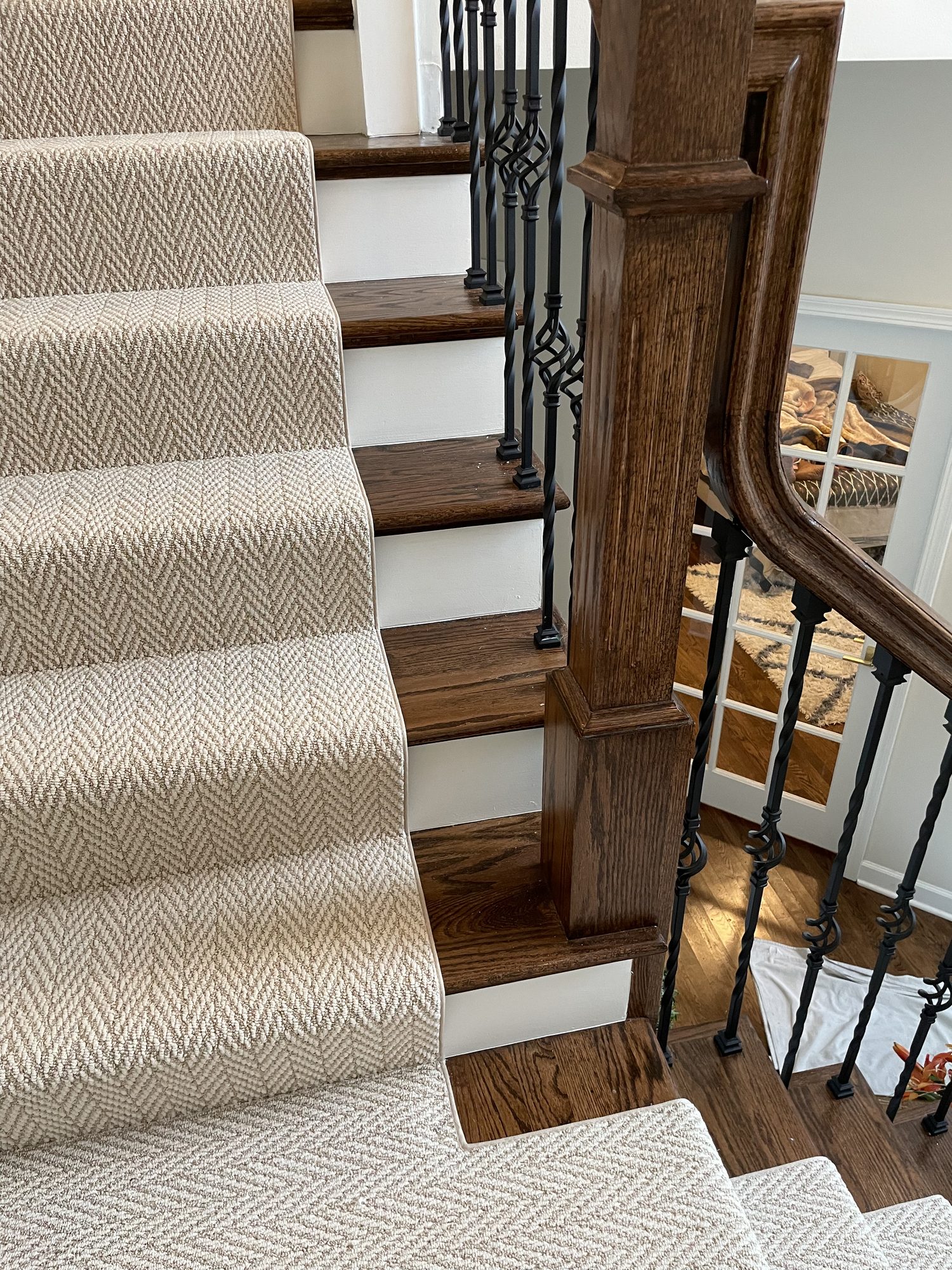 Bound runner edge beside the newel post Close side view of a bound herringbone runner on oak stair treads next to the newel post and curved handrail